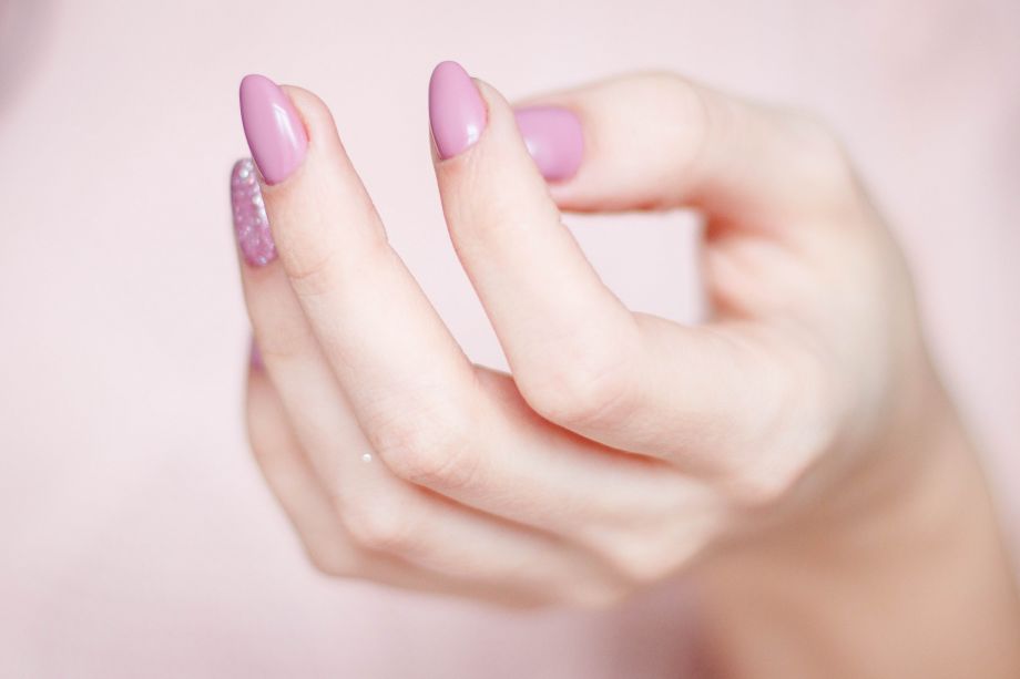 zarte helle Hand mit rosafarbenen Fingernägeln