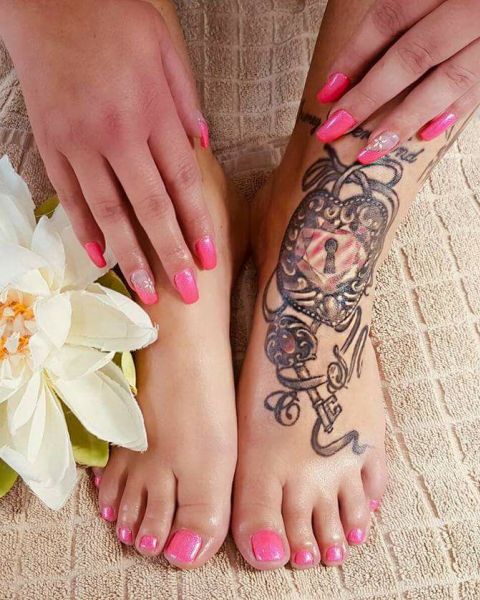 Füsse und Hände mit pink lackierten Fingernägeln und einem Tattoo auf dem rechten Fuss